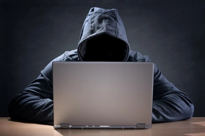 05 a hacker wearing a hoodie sits in front of an open laptop