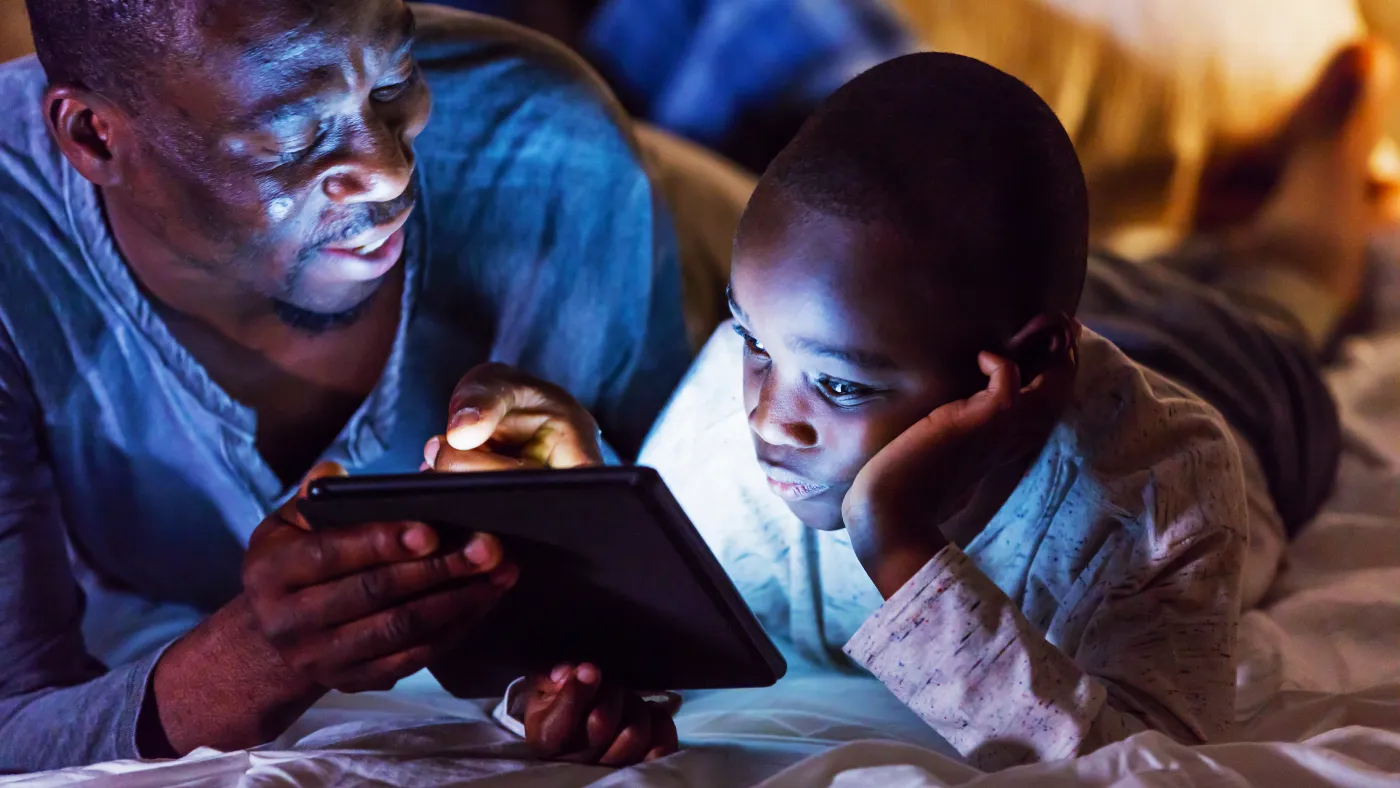 Anak dan orang tua menggunakan tablet bersama di perpustakaan